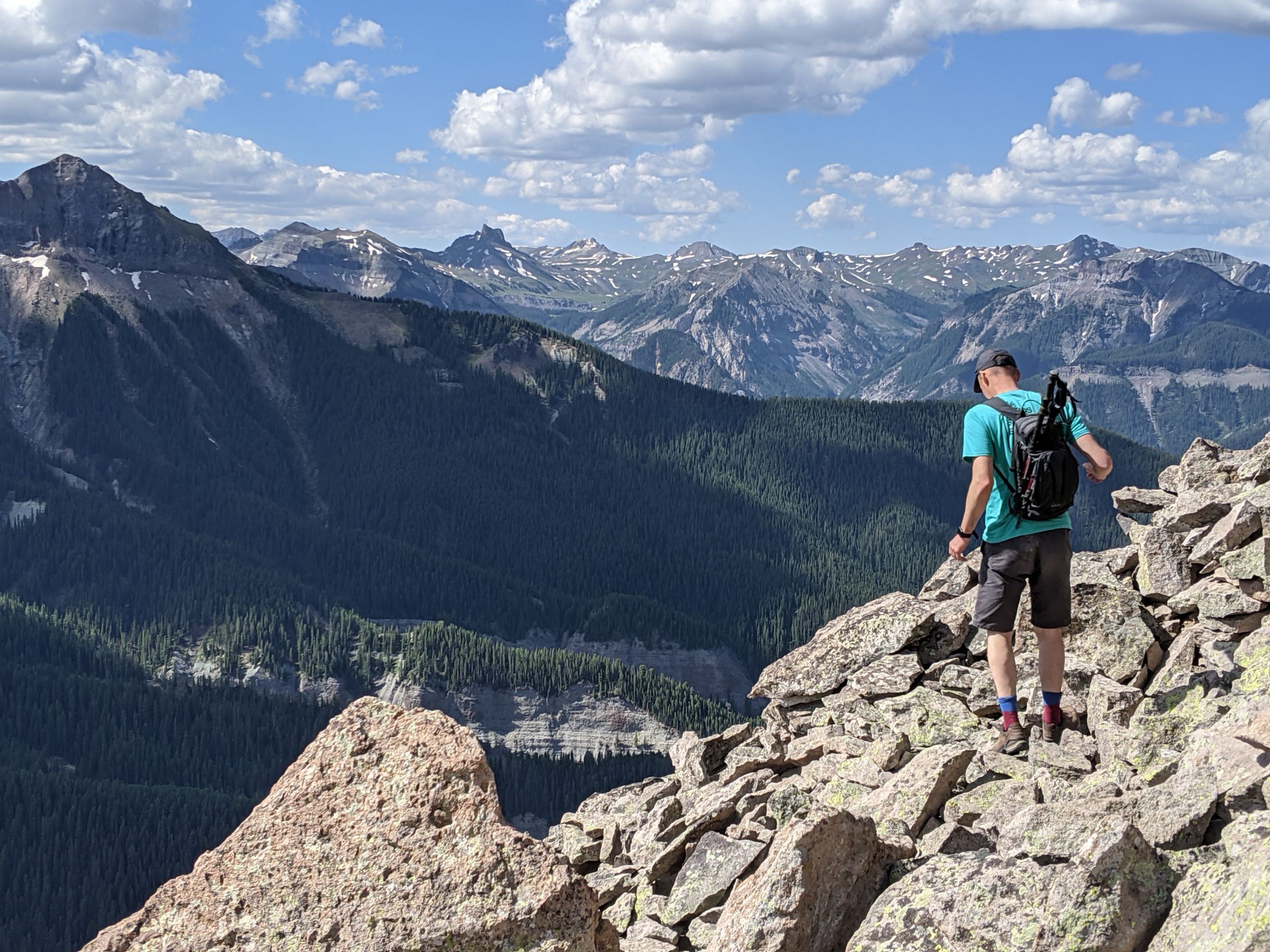 A hiker on the foreground in front of a mountain range.